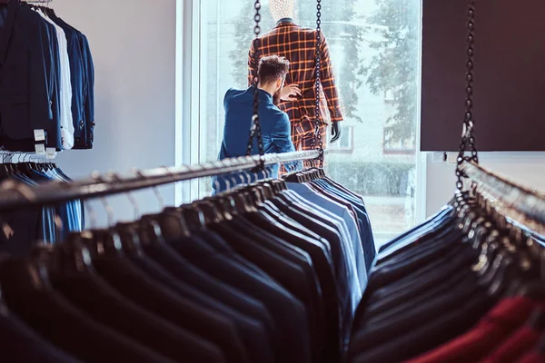 Stylish bearded seller care about suit on a mannequin in a menswear store. — Stock Photo, Image