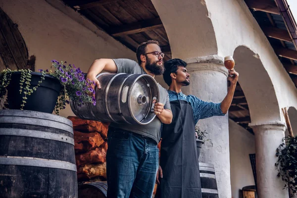 Zwei Brauer im Vorfeld stehen draußen und überprüfen die Qualität des gebrauten Getränks in der Brauerei-Fabrik. — Stockfoto