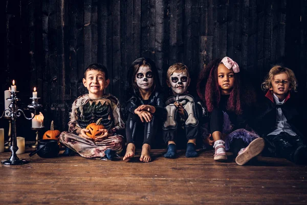 Fiesta de Halloween con niños de grupo que se sientan juntos en un piso de madera en una casa vieja. Concepto Halloween . — Foto de Stock