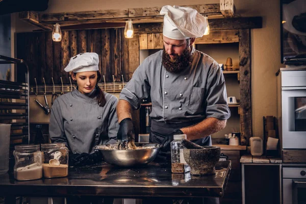 Chef amasando masa en la cocina. Chef enseñando a su asistente a hornear el pan en la panadería . —  Fotos de Stock