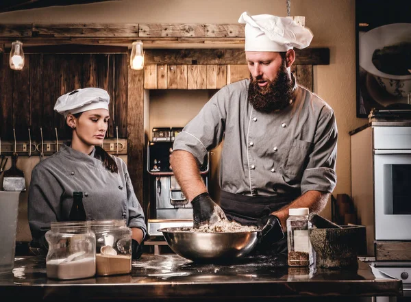 Chef-kok kneden van deeg in de keuken. Chef-kok onderwijs zijn assistent te bakken het brood in de bakkerij. — Stockfoto