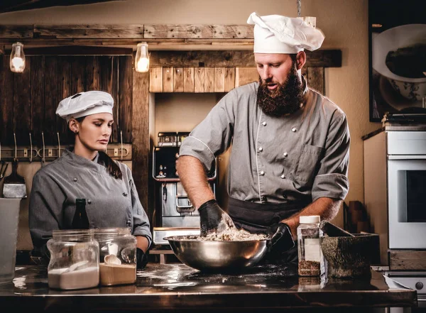 Chef amasando masa en la cocina. Chef enseñando a su asistente a hornear el pan en la panadería . —  Fotos de Stock