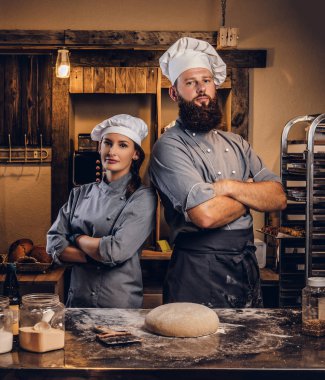 Şef asistanı aşçı üniformalı hazır hamur ekmek içinde tabloyla yakınındaki çapraz silah ile poz ile.