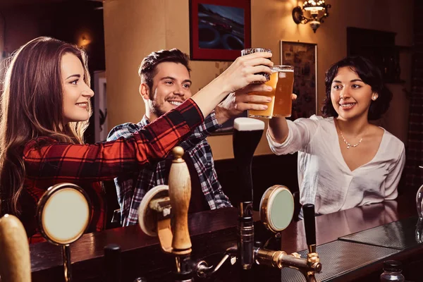 Happy multiracial friends making a toast with beer at bar or pub.