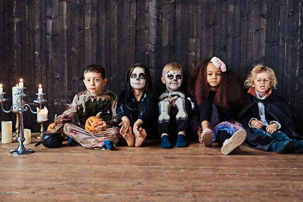 Halloween party a csoport gyermekek akik együtt ültek egy fa padló, a régi házban. Halloween koncepció. — Stock Fotó