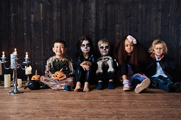 Fiesta de Halloween con niños de grupo que se sientan juntos en un piso de madera en una casa vieja. Concepto Halloween . —  Fotos de Stock