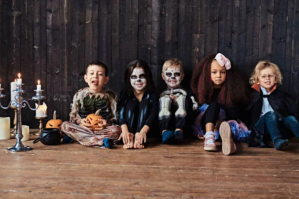 Fiesta de Halloween con niños de grupo que se sientan juntos en un piso de madera en una casa vieja. Concepto Halloween . —  Fotos de Stock