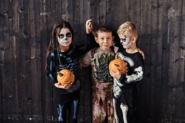 Tres niños lindos en trajes de miedo durante la fiesta de Halloween en una casa vieja . —  Fotos de Stock