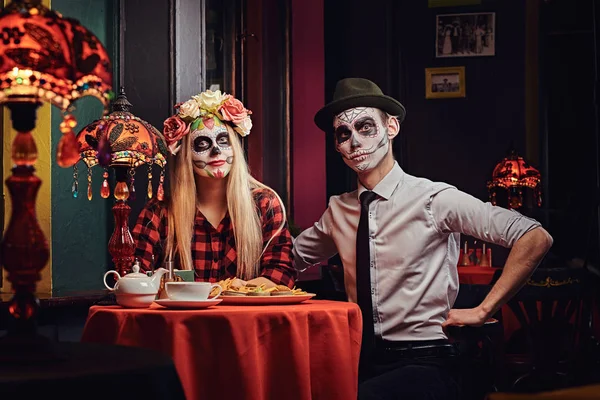 Joven pareja atractiva con maquillaje no muerto comiendo nachos durante las citas en un restaurante mexicano . — Foto de Stock