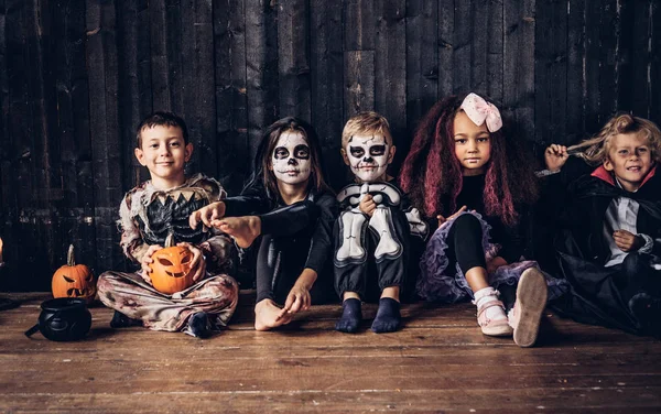 Fiesta de Halloween con niños de grupo que se sientan juntos en un piso de madera en una casa vieja. Concepto Halloween . — Foto de Stock