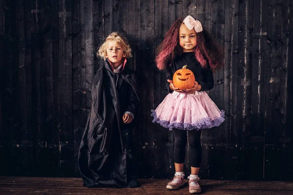 Linda pareja de niños pequeños en trajes de miedo posando en una casa vieja . — Foto de Stock