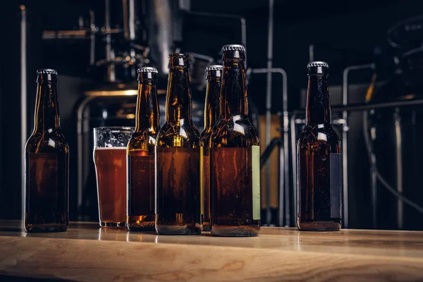 Пляшки та келих крафтового пива на дерев'яній барній стійці на пивоварні Інді . — стокове фото