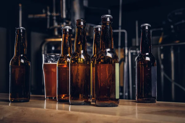 Flaschen und Glas Craft Beer auf Holztheke in der Indie-Brauerei. — Stockfoto