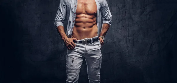 Photo recadrée d'un homme sportif avec un corps musclé en chemise déboutonnée et un jean posant en studio . — Photo