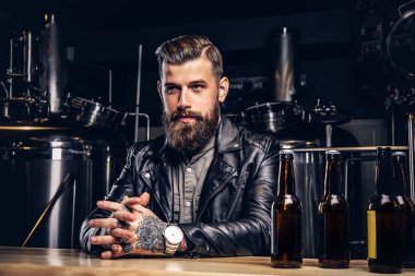 Şık sakallı motorcu indie bira sayacında bar oturan siyah deri ceket giymiş.