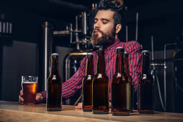 照片与工艺啤酒瓶的前景和胡子男性饮酒的背景. — 图库照片