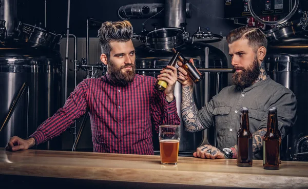 Twee stijlvolle bebaarde hipsters vrienden drinken bier samen in indie brouwerij. — Stockfoto