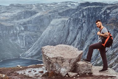 Dağın zirvesine Norveç fiyordu şaşırtıcı bir görünümünü üzerinde turist duruyor.