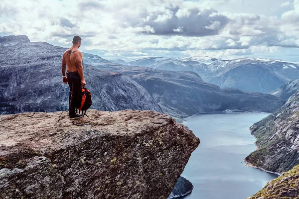 Uomo turistico in piedi nel Trolltunga e gode di una splendida vista sul fiordo norvegese . — Foto Stock