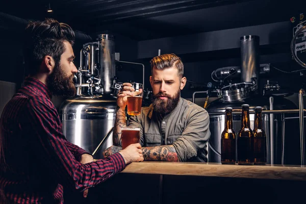 Двоє стильних друзів бородатих хіпстерів п'ють пиво разом на пивоварні Інді . — стокове фото