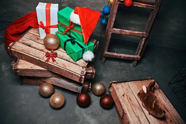 Gift boxes, tree balls, hat and bag with vintage wooden boxes and ladder.