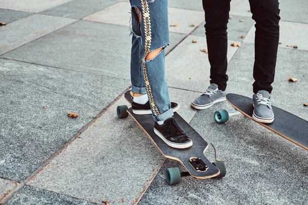 Fritid och sport koncept - närbild foto av en trendig klädda teen par med skateboards på gatan. — Stockfoto