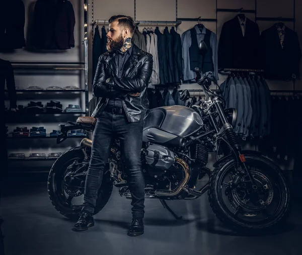 メンズの衣料品店でバイクをスポーツ レトロ近く交差腕を持つ残忍な男性に身を包んだ黒ジャケット ポーズ. — ストック写真