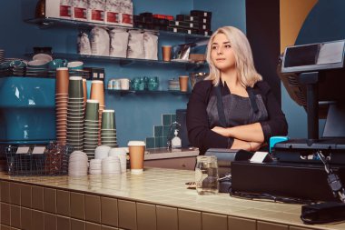 Güzel deneyimli kadın barista kahve dükkanında çapraz kollu önlük ayakta.