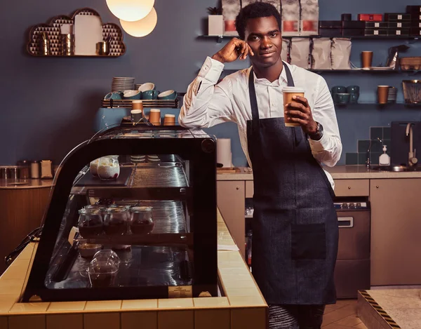 Afrika barista kahve ile iş günü süre üstünde belgili tanımlık sayaç kahve dükkanında eğilerek sonra rahatlatıcı kameraya gülümseyen.