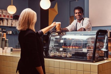 Afro-Amerikan barista kahve kadın müvekkilinin trendy kahve dükkanında vererek.