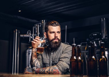 Dövmeli hippi erkek şık sakal ve saç barda oturmuş bira içme indie bira sayaç.