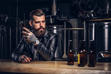 Şık sakallı motorcu indie bira sayacında bar oturan siyah deri ceket giymiş.