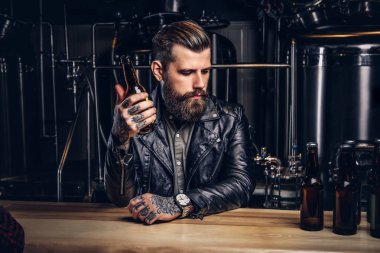 Şık sakallı motorcu indie bira sayacında bar oturan siyah deri ceket giymiş.