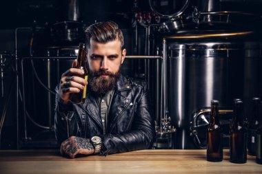 Şık sakallı motorcu indie bira sayacında bar oturan siyah deri ceket giymiş.