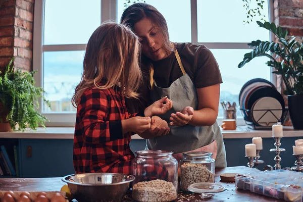 Happy mom cooking with her little daughter in loft style kitchen at morning.