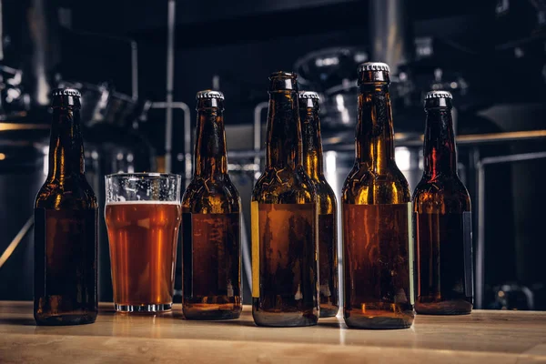 Bottles and glass of craft beer on wooden bar counter at the indie brewery. — Stock Photo, Image