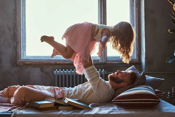 Dad and daughter in bed. Father playing with adorable daughter in bedroom.