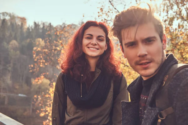 Portrait of young happy hikers walking at the beautiful autumn forest at sunset.
