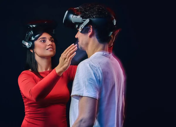 Joven chica alegre ajusta gafas de realidad virtual en su novio. Pareja de jugadores con auriculares VR . — Foto de Stock