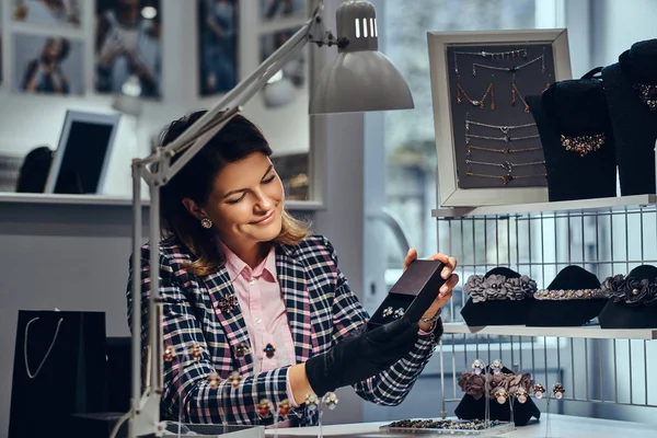 Kobiece Biżuteria pracownik pokazuje piękne cenne kolczyki z kamieniami w luksusowy sklep jubilerski. — Zdjęcie stockowe