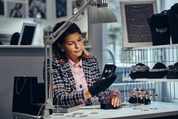 Női ékszerek munkavállaló mutatja gyönyörű értékes drágakövek fülbevaló egy luxus ékszer áruház. — Stock Fotó