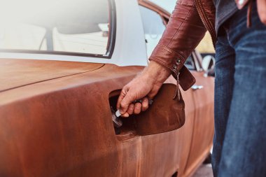 Erkek el yakıt ikmali için ayarlanmış bir retro arabanın benzin kapağını açar.