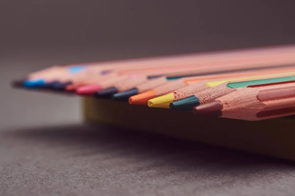 Lápis multicoloridos deitados em um bloco de notas amarelo . — Fotografia de Stock