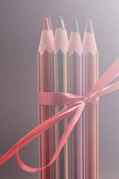 Grupo de lápis multicoloridos decorados com fita de presente vermelho . — Fotografia de Stock
