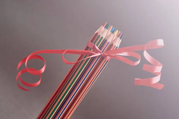 Skupina barevné tužky zdobené červenými Dárková stuha. — Stock fotografie