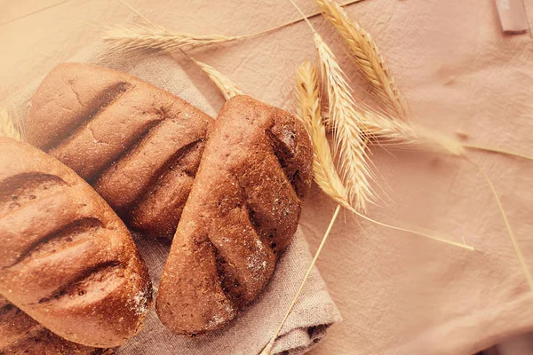 Freshly baked buns and spikelets of wheat lying on a cloth. — Stock Photo, Image