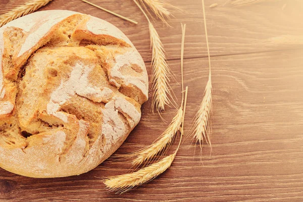 Freshly baked bread and spikelets of wheat. — Stock Photo, Image