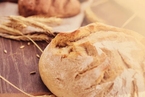 Deliciosos productos de panadería fresca y espiguillas de trigo sobre fondo de madera . — Foto de Stock