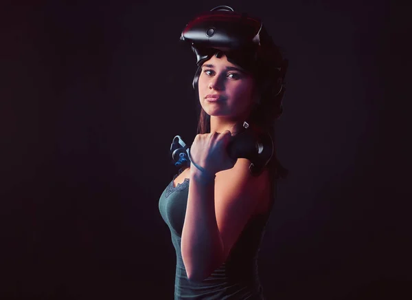 Mulher bonita vestindo fone de ouvido realidade virtual e mantém joysticks, posando câmera ar . — Fotografia de Stock