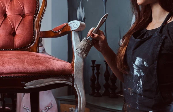 Artista donna che dipinge sedia vintage in colore bianco con pennello in laboratorio . — Foto Stock